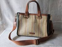 Front view of new Calvin Klein handbag showing woven fabric with vertical stripes and brown leather details.