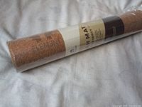 Rolled ELEMENT natural cork yoga mat with clear packaging, showing label with brand and product details.