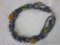 Photo of the full necklace arranged in a circle showing the multi-strand freshwater pearls and polished stones, highlighting color and texture.