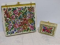 Both vintage embroidered items placed side by side, showing full front floral embroidery and gold clasps.