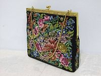 Front view of the vintage handbag showing colorful floral needlepoint embroidery and gold-tone frame with chain.