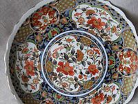 Full view of vintage large porcelain footed plate with handpainted Imari floral motifs and intricate gold lattice patterns.