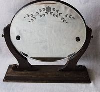 Front view of the round mirror showing the floral etching and wooden frame base.