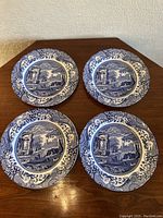 Four Spode Italian blue and white salad plates arranged on wooden table showing top design.