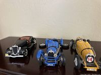 Front view of three model Bugatti cars showing color and detailing.