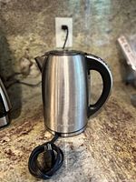 Front view of the stainless steel Cuisinart cordless electric kettle with power cord coiled in front.