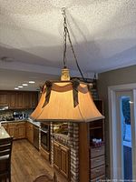 Full view of the hanging French rustic chandelier in kitchen area with wooden floors and cabinets in background.