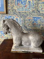 Side view of the large horse bust sculpture showing profile and textured surface on base and sculpture.