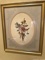 Front view of gold wood framed floral print with purple and yellow flowers, oval embossed mat