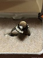 Front angled view of the sterling silver ring highlighting the oval tanzanite and clear stones