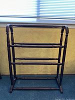 Front view of the vintage quilt rack showing its full structure and cherry wood finish against a neutral background.