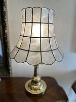 Front view of table lamp with illuminated capiz shell shade revealing mother of pearl finish and scalloped edges