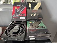 Five HDMI cables in original packaging, showing two black/silver braided cables and one white cable