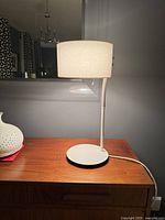 Front view of the vintage white IKEA Ledet table lamp on a wooden surface, showing round base and fabric lampshade in upright position.