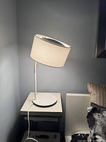 Side view of the white IKEA Ledet lamp showing the round base and tilted shade.