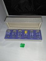 Set of six lead crystal napkin rings displayed in original box with cream exterior and purple interior lining.