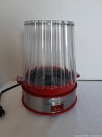 Front view of the Cuisinart popcorn maker showing clear plastic ribbed lid and red base with stainless steel front panel.