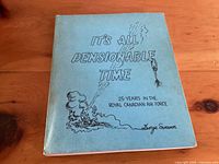 Photo of a softcover book with a light blue cover, titled 'It's All Pensionable Time' with cartoon drawings.