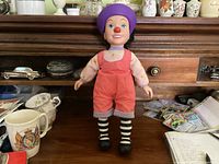 Front view of Loonette doll on wooden surface with ceramic cups and papers in background.