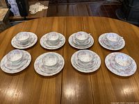 Full set laid out on table showing cups with saucers, large plates and smaller plates.