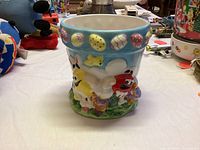Front angle of ceramic vase with Red and Yellow M&M's characters and Easter egg design at rim