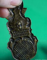 Close-up photo of back of paperclip showing engraved inscription and S.I.N scratch marks