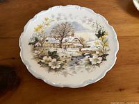 Top view of Royal Albert Winter plate showing detailed winter scene with cottage, trees, and floral border.