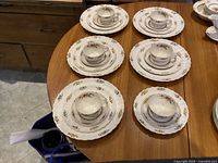 Full set arranged on table showing 5 dinner plates, 6 salad plates, 6 cups with saucers in Spode Rosalie floral pattern.