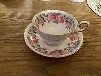 Photo of the vintage Tuscan cup with pink rose and floral pattern on a wooden surface.
