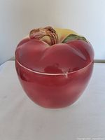 Photo of the front side of the ceramic apple cookie jar showing the red color and stem detail.