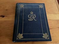 Photo of blue hardcover booklet with gold royal cypher and maple leaf decorations