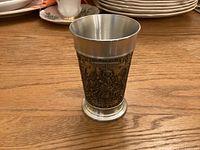 Front view of pewter tumbler showing detailed embossed design.