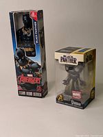 Two Black Panther figurines side by side in original boxes. Taller Hasbro Avengers Titan Hero Series figure shows some box wear. Funko Wobbler exclusive edition in pristine box.
