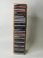 Wooden rack filled with 35 CDs showing spines with artist and album names