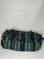 Dakine duffle bag shown from front, displaying striped fabric pattern and front zipper pocket.