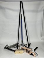 Full view of all items in the lot, showing driveway rollers with extension poles, brush, caulking gun, and grease tool.