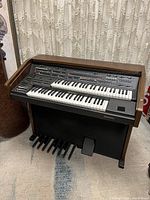 Front view showing dual keyboards, control panel, speaker housing and pedalboard