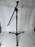 Front angled view of black adjustable microphone stand with tripod base showing boom arm and adjustment knobs.