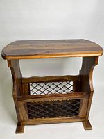 Solid wood side table showing side profile and metal mesh magazine rack.