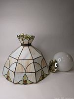 Full view of the pearl toned stained glass pendant light shade next to the accompanying white globe and metal ceiling fastener.