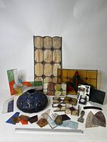 Full view of stained glass fragments, partial panels, and Tiffany style lamp shade on white surface