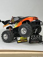 Side and front view of the Tyco RC Fugitive remote control monster truck showing its large tires, black front bumper, flame decals, and Tyco RC flag.