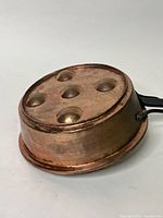 Side view of the vintage copper egg poacher showing the rounded egg holders and copper surface with tarnishing.