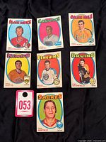 Lot of seven 1971-72 OPC hockey cards laid out on black fabric background, showing front of cards, players' headshots, team logos, and colorful background ovals