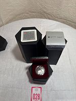 Photo of the black hexagonal case containing the proof silver dollar coin, the case lid, and the outer packaging box.