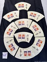 Photo showing all ten miniature sheets arranged in concentric circles on black fabric, each with two stamps and Chinese characters.