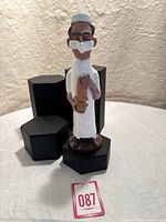 Front and side view of the Chelsea Pottery figurine showing the male doctor wearing surgical mask and holding a baby.