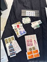Full lot showing several groups of Canadian mint stamps spread on cloth surface, with one strip in black holder.