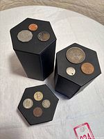 Three octagonal display stands holding nine coins