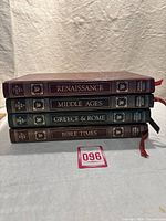 Four hardcover volumes stacked horizontally showing titles Bible Times, Greece & Rome, Middle Ages, Renaissance on spines with gold embossed text and red to green leatherette binding.
